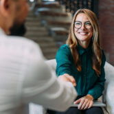 Business people shaking hands in the office. Business persons handshaking during a meeting in modern office.